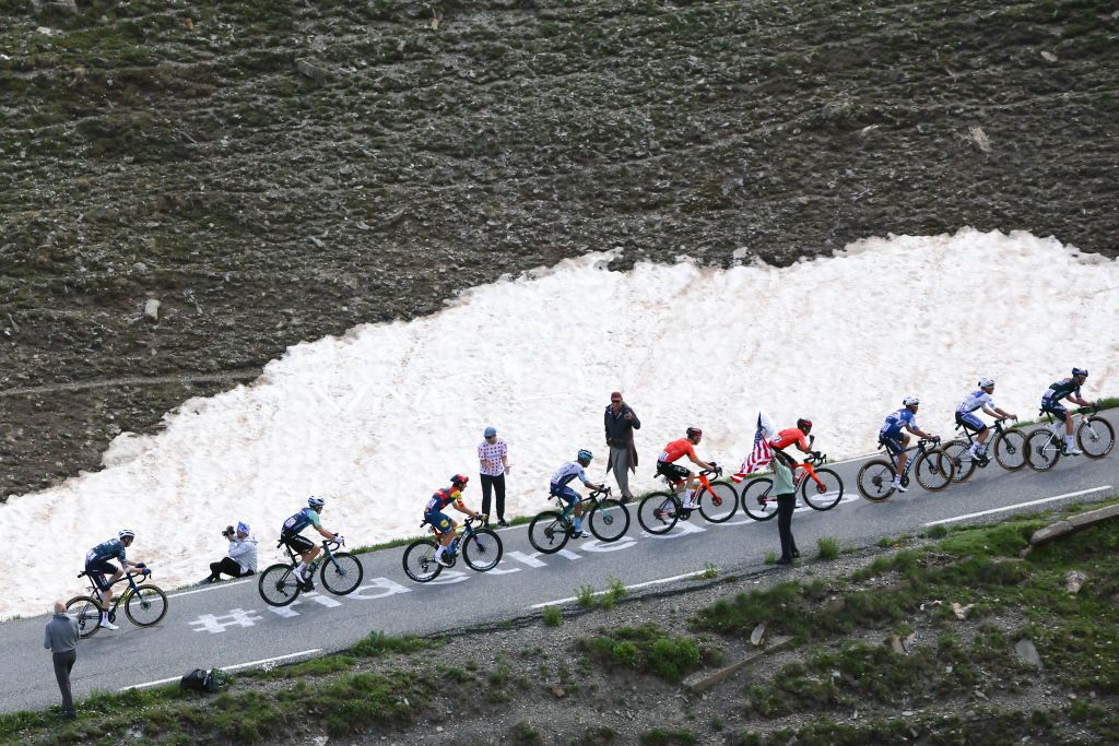 The lead breakaway cycles past a patch of snow in the Galibier ascent during the 4th stage of the 111th edition of the Tour de France cycling race, 140 km between Pinerolo in Italy, and Valloire in France, on July 2, 2024. (Photo by Anne-Christine POUJOULAT / AFP)