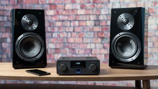 SVS Prime Wireless Pro amplifier with speakers against brick background
