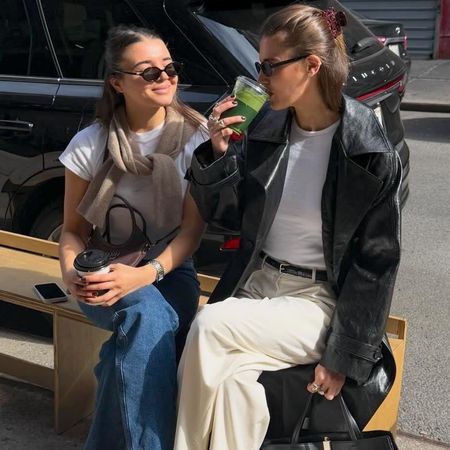 style influencer Coco Schiffer and her sister sit on a sidewalk bench in NYC wearing chic casual outfits for spring 2026 with white T-shirts