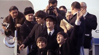 The Beatles surrounded by press photographers stepping out of a jet