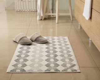 White abstract pattern bath mat on floor with slippers