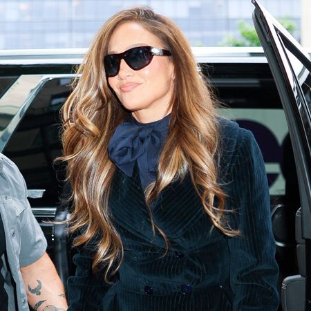 Jennifer Lopez steps out of a car wearing lace footless tights with a velvet tuxedo minidress and a Hermes bag.