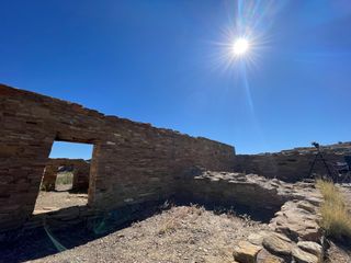 sun in blue sky surrounded by ancient ruins.