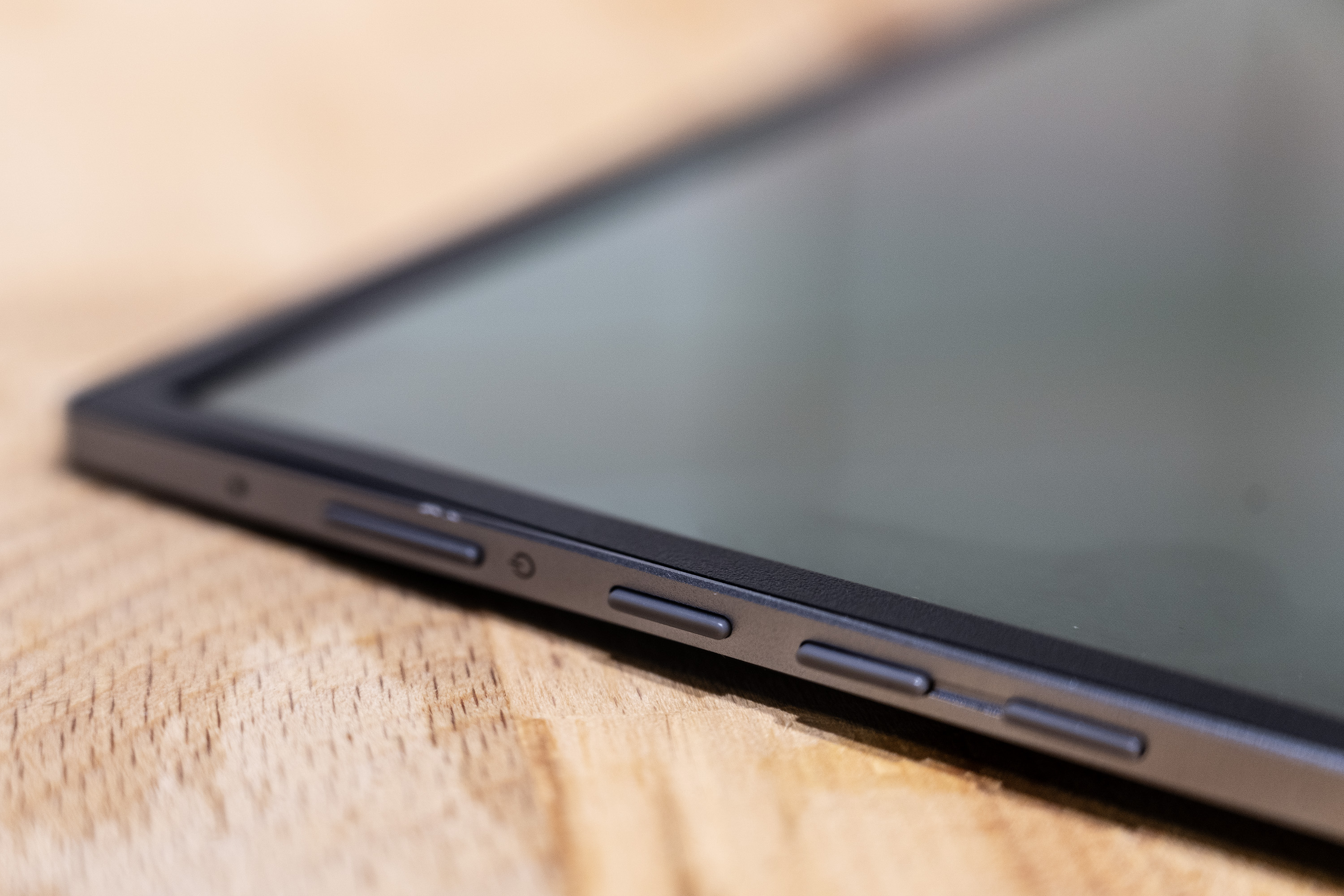 A black and silver ASUS ZenScreen MQ16AH portable monitor on a wooden brown desk