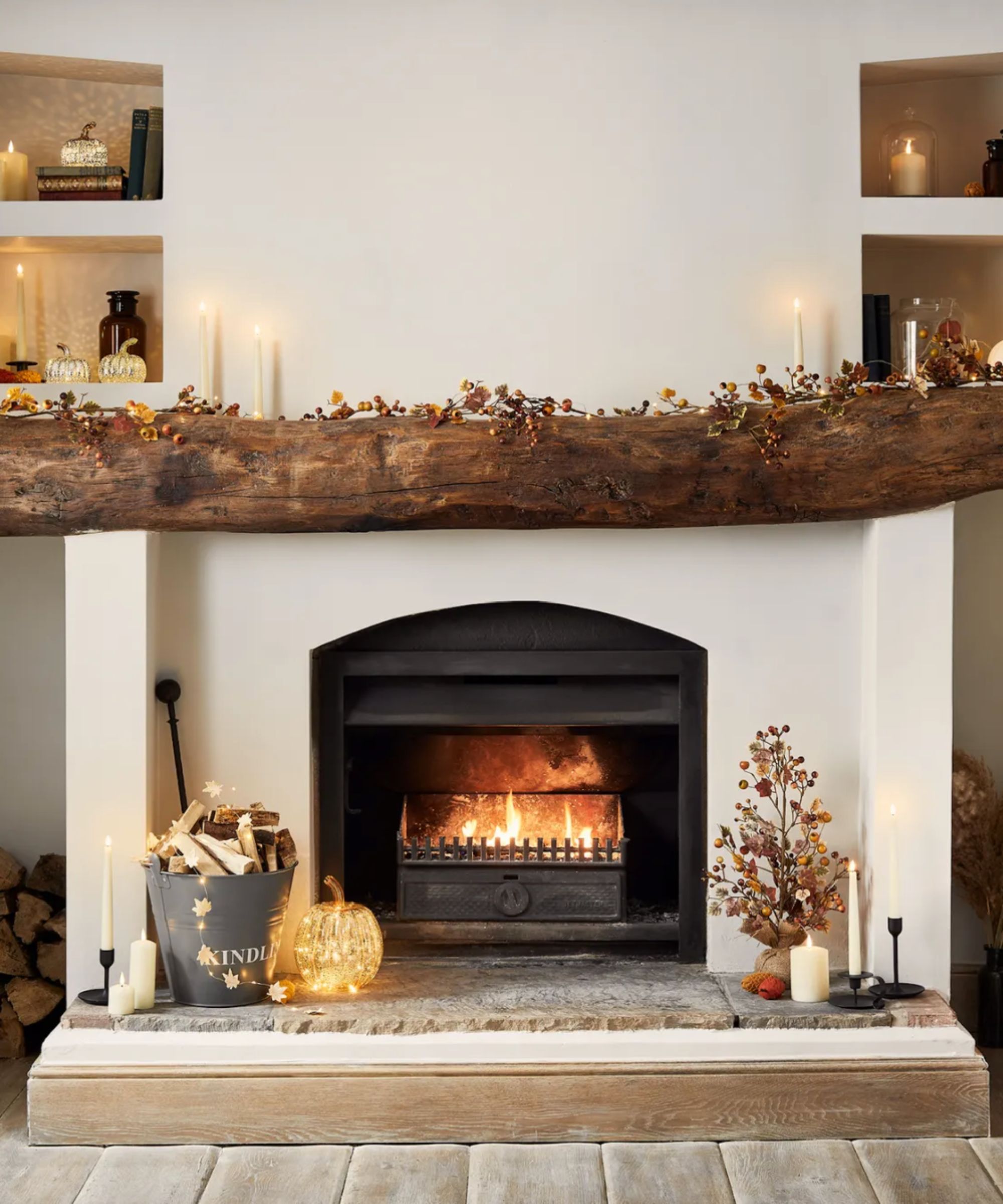 A fireplace with a rustic wooden beam decorated with autumn garlands