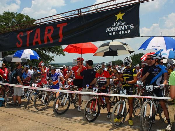 Team support staff hold umbrellas over their riders to keep the hot sun off of them.