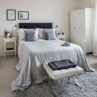 Bedroom with cream walls and grey bedding and grey rug