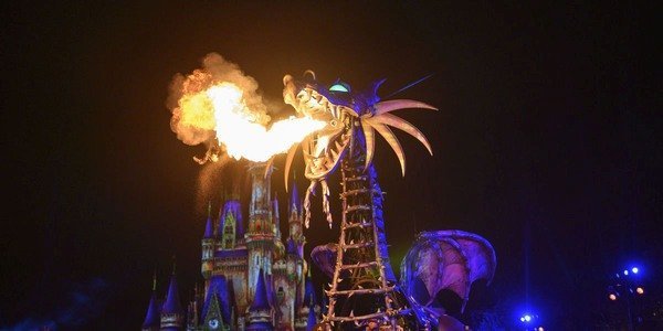 A dragon breathing fire during a show in front of Cinderella&#039;s Castle at Disney.