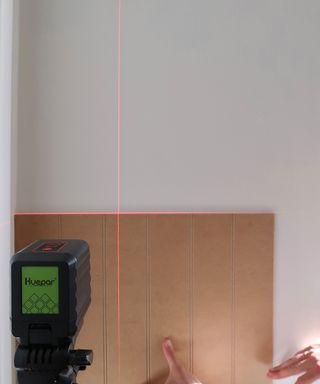 Claire Douglas using a Huapar laser level on wall to DIY a wall panelling project