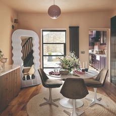A pink dining area with a white round table and round jute rug