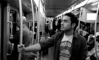 Black and white image of Guiseppe Conca holding a handrail in a train carriage