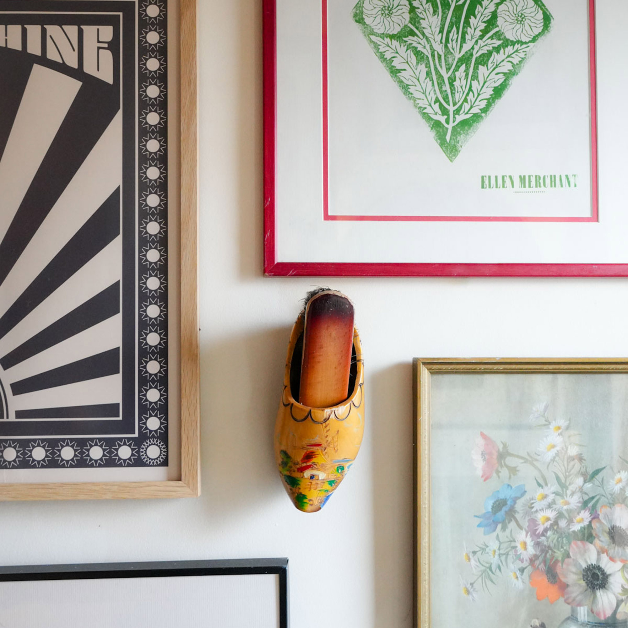 gallery wall with framed art and a clog hanging on the wall