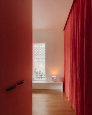 Interior view of Le Marais apartment by Saba Ghorbanalinejad with red curtains and wood floors