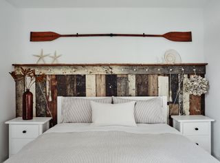 bedroom with nautical style driftwood headboard and decorative oar above bed and striped linen