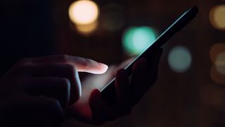Close up of woman's hand scrolling on phone late at night