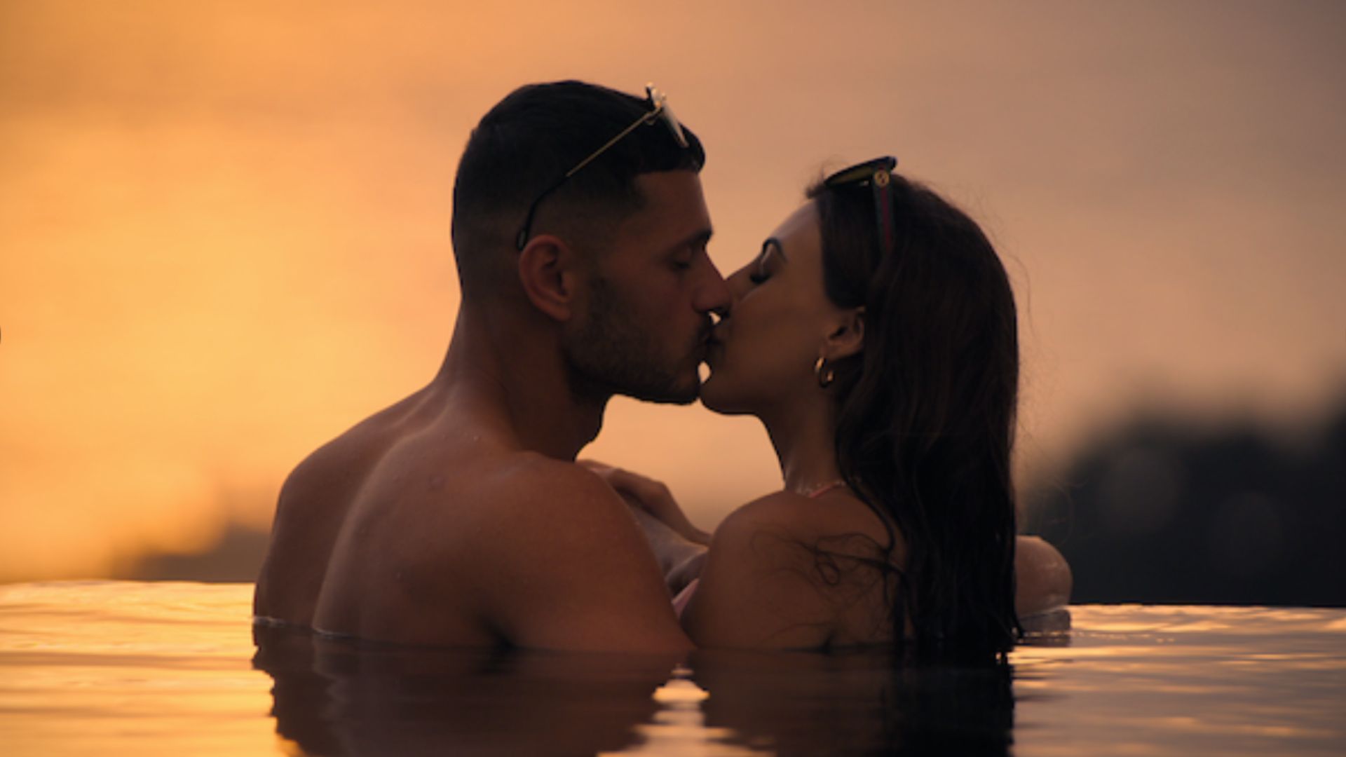 an image of two of the contestants from Love Is Blind series 2 kissing in an infinity pool overlooking over a sunset