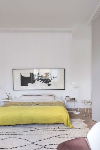 White bedroom with low furniture and modern artwork