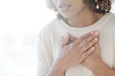 Mid adult woman touching her chest.