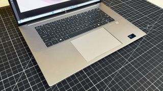 HP ZBook Studio 16 G11 mobile workstation on a white desk with a black table mat, against a yellow backdrop.