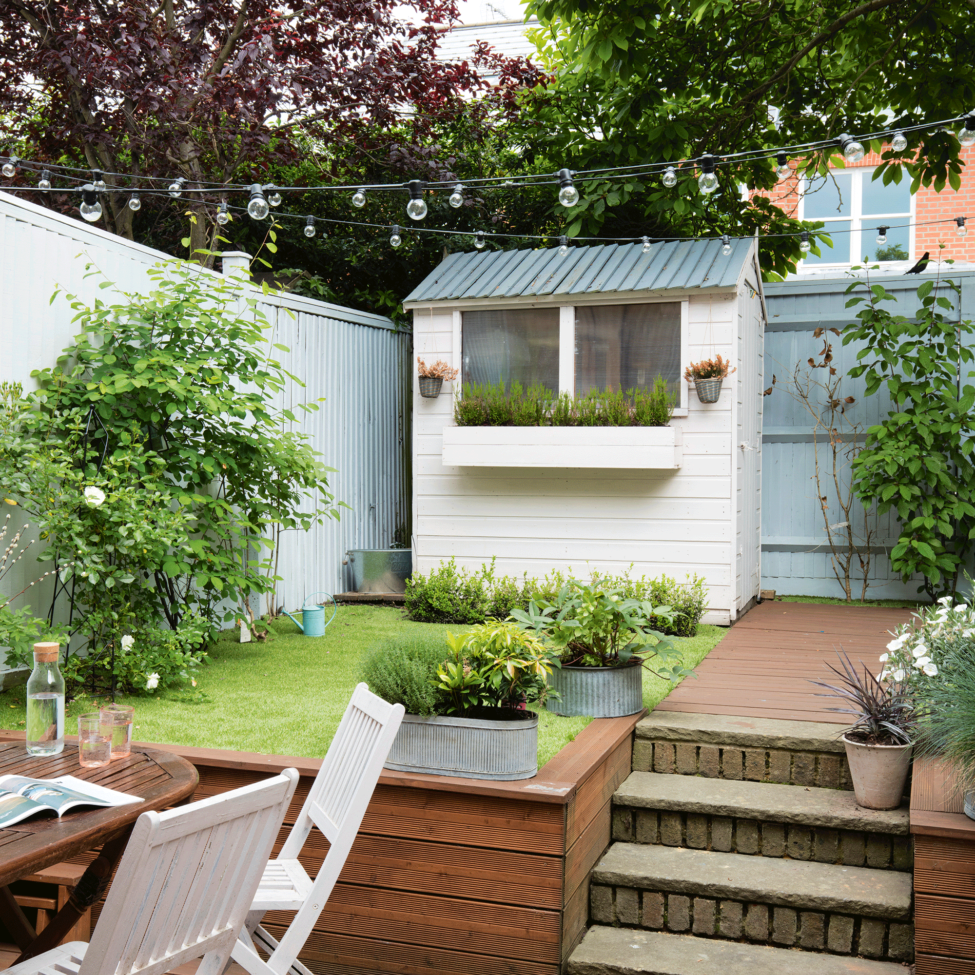 White shed at the back of a small garden