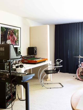 Arctic Monkeys drummer Matt Helders' music studio with a blue curtain and Mies Van Der Rohe black leather cantilevered chair