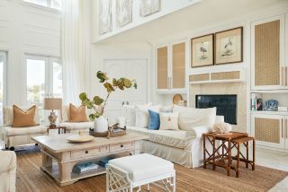 A neutral living room with coastal themed decor, white linen sofas, and blue accents