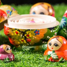 Russian dolls split apart showing central doll on grass