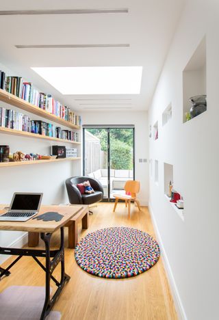 A multi-purpose garage conversion with a desk, chairs and a wooden floor overlooking over a garden by Architect Your Home