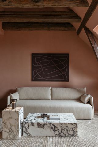 Terracotta wall with brown artwork and beige sofa