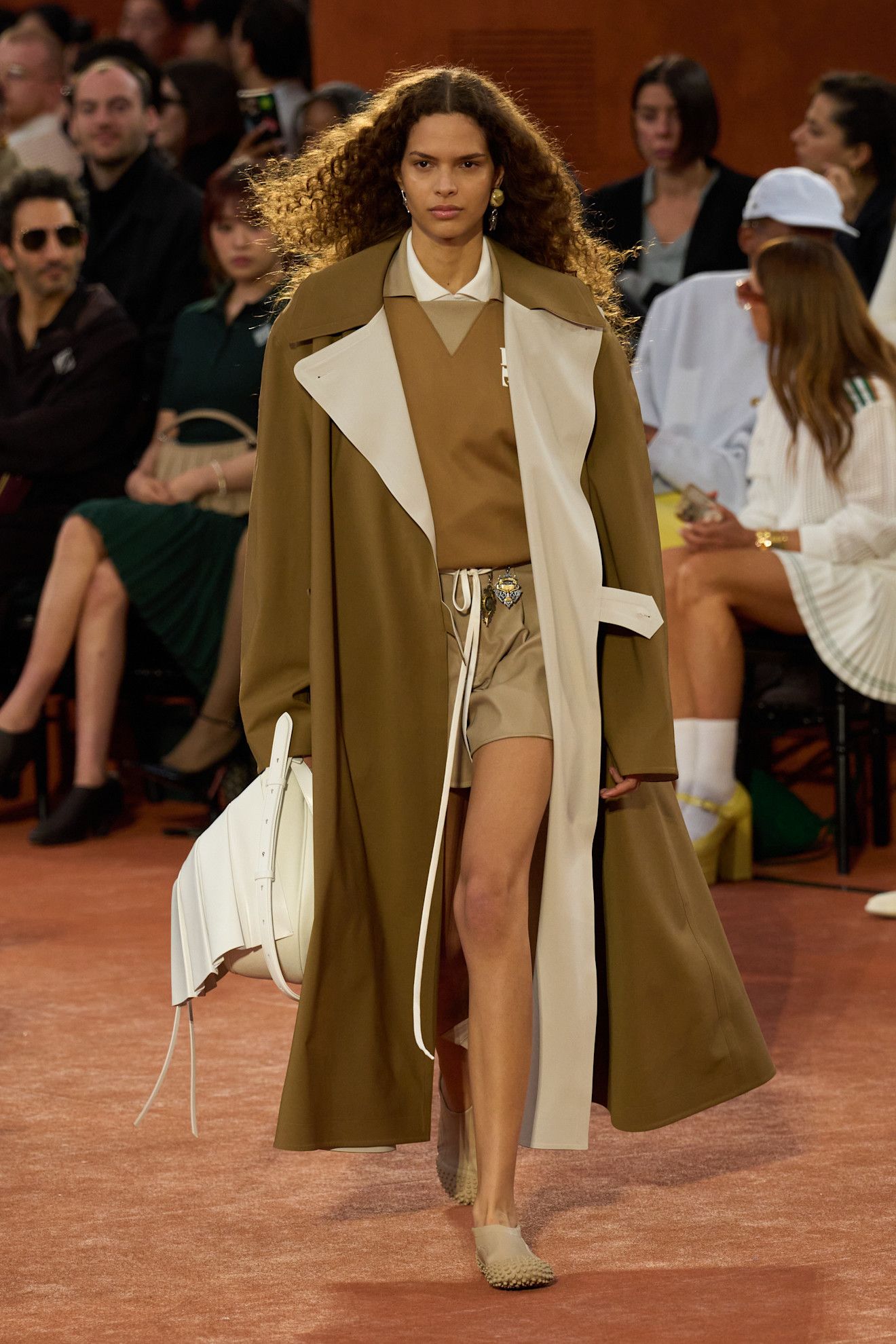 Lacoste runway model carrying a white handbag