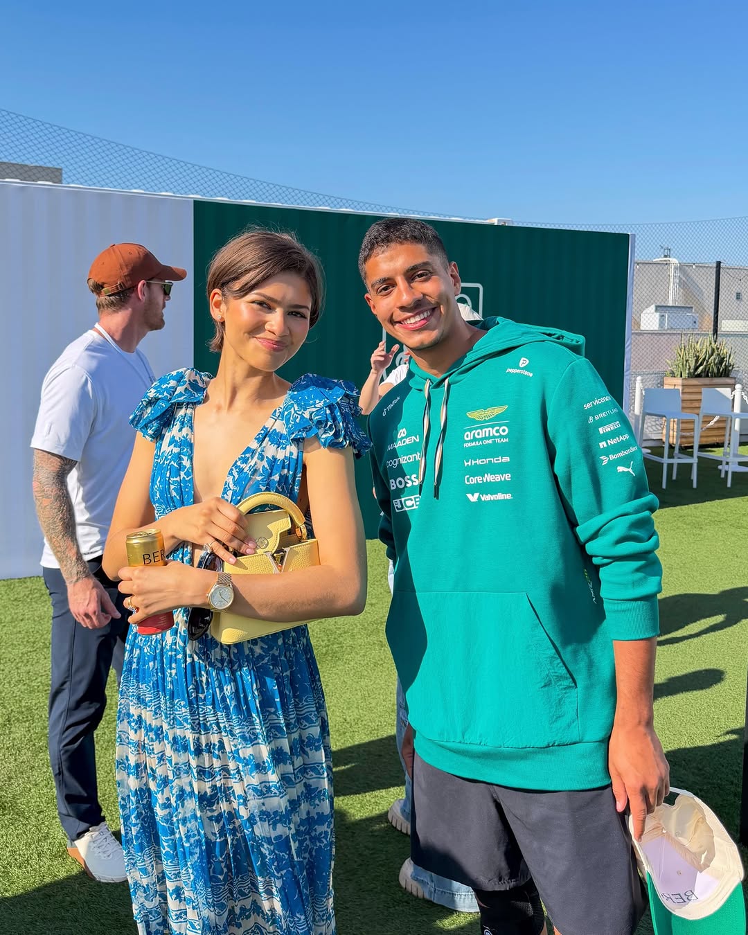 Zendaya posed with a fan at tom holland's tennis event in a blue sundress, The Row Mary Janes, and a butter yellow Louis Vuitton bag