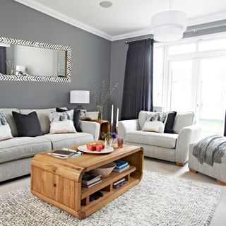 Dark grey living room with light grey sofas and a textured grey rug