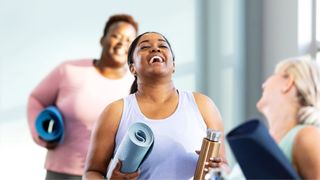 Woman laughing and walking with friends holding a yoga mat