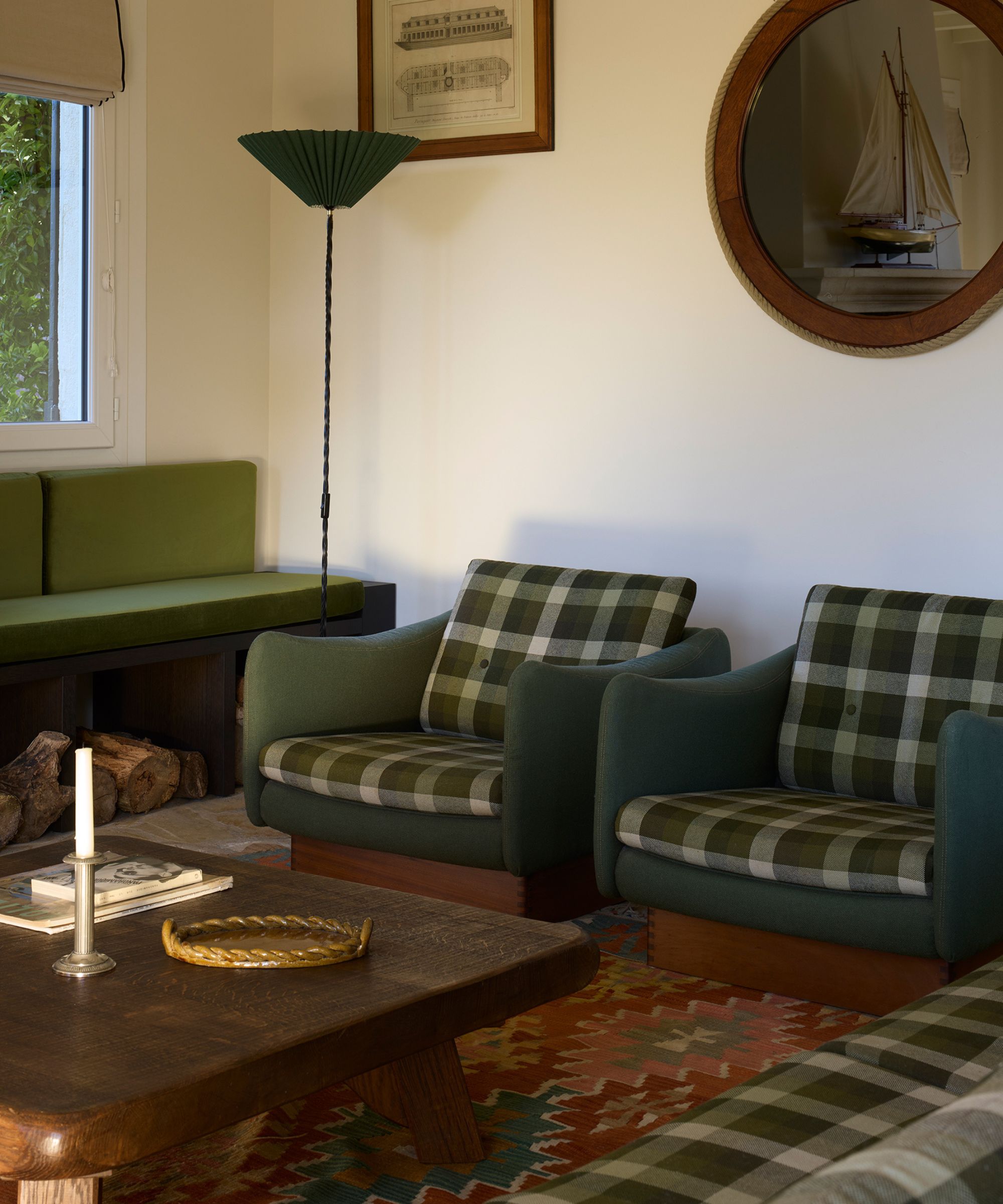 a neutral sitting room in a cottage in France with green bench seat, green plaid armchairs, vintage wooden furniture and nautical themed art
