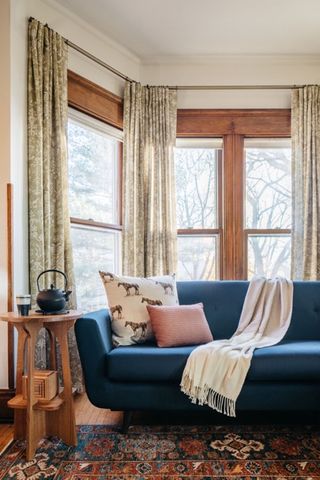 living room with blue sofa and wooden side table with sage curtains