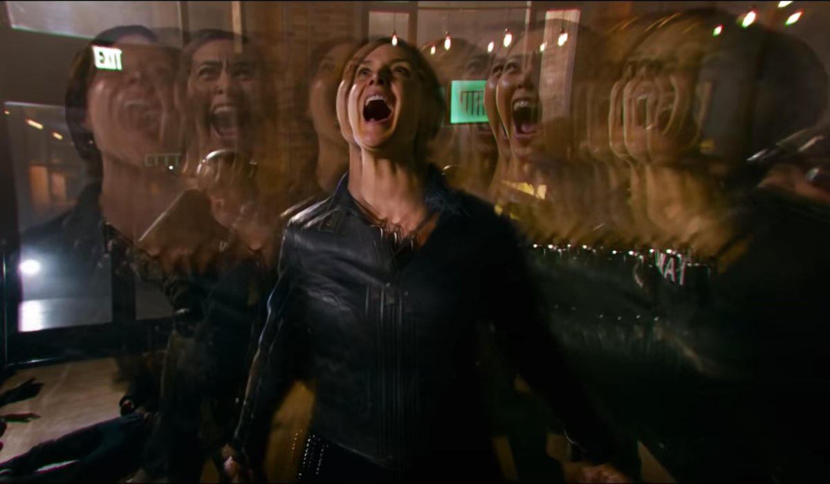 Carrie-Anne Moss screams surrounded by her image in The Matrix Resurrections.