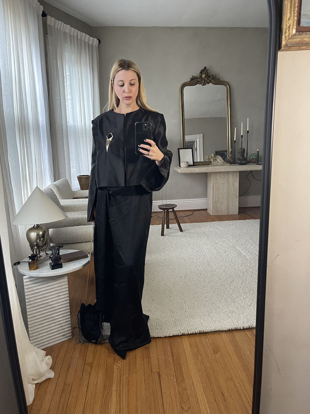 Kerri Pieri in a black skirt, black jacket, and gold brooch