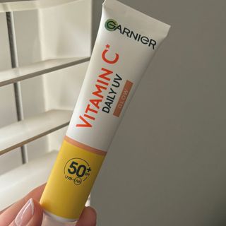 Laura holding Garnier Ambre Solaire Vitamin C Daily UV Brightening Fluid Glow SPF 50+ - best sun cream