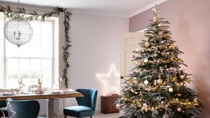 An open-plan living-dining room with decorated Christmas tree with table and garland window decoration