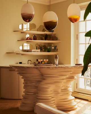 a home bar made for irregular slabs, with glass light orbs above, and shelving with pond mirror shapes behind