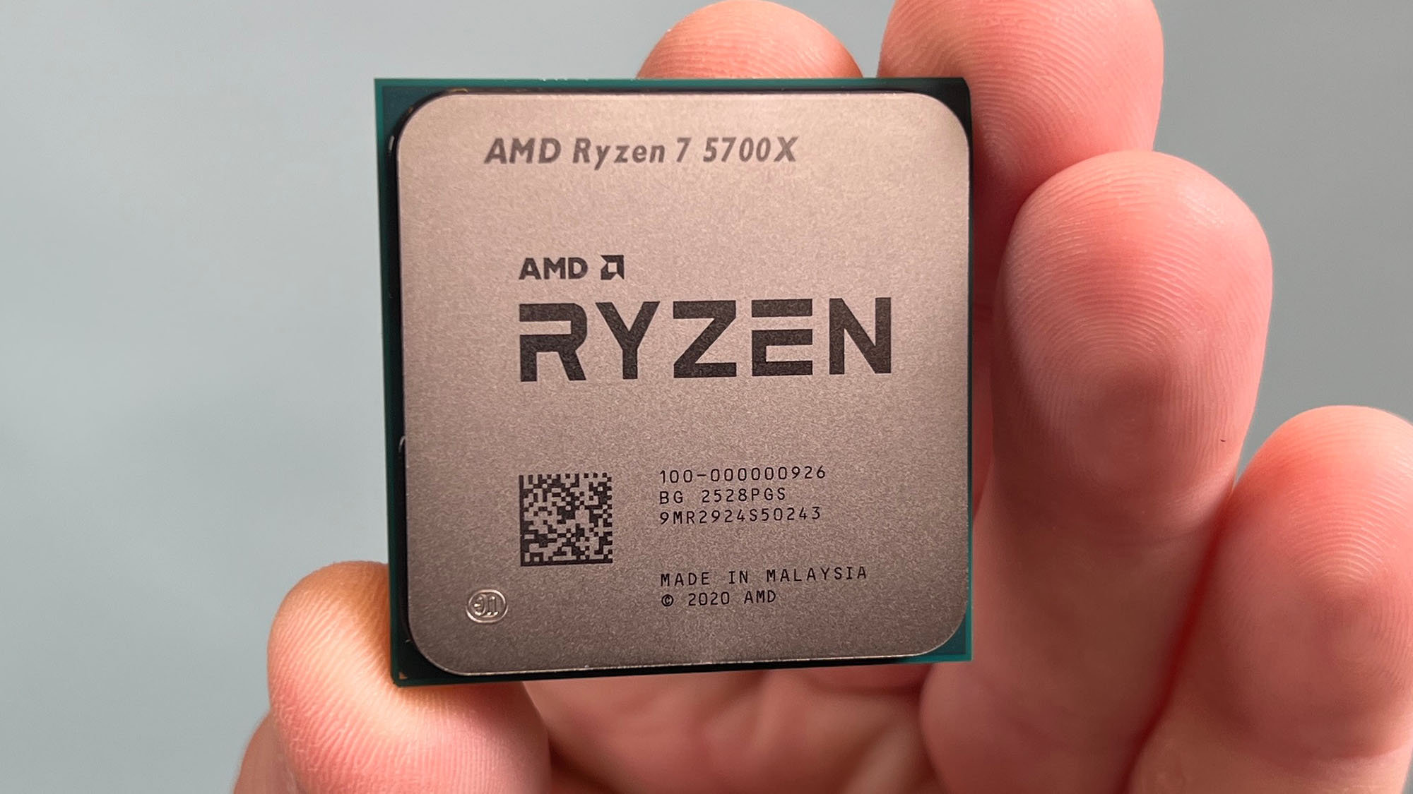 An AMD Ryzen 7 5700X held in a masculine hand