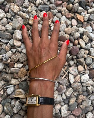 @tylynnnguyen's hand featuring a Charlotte Chesnais bracelet and gold and black Cartier watch.