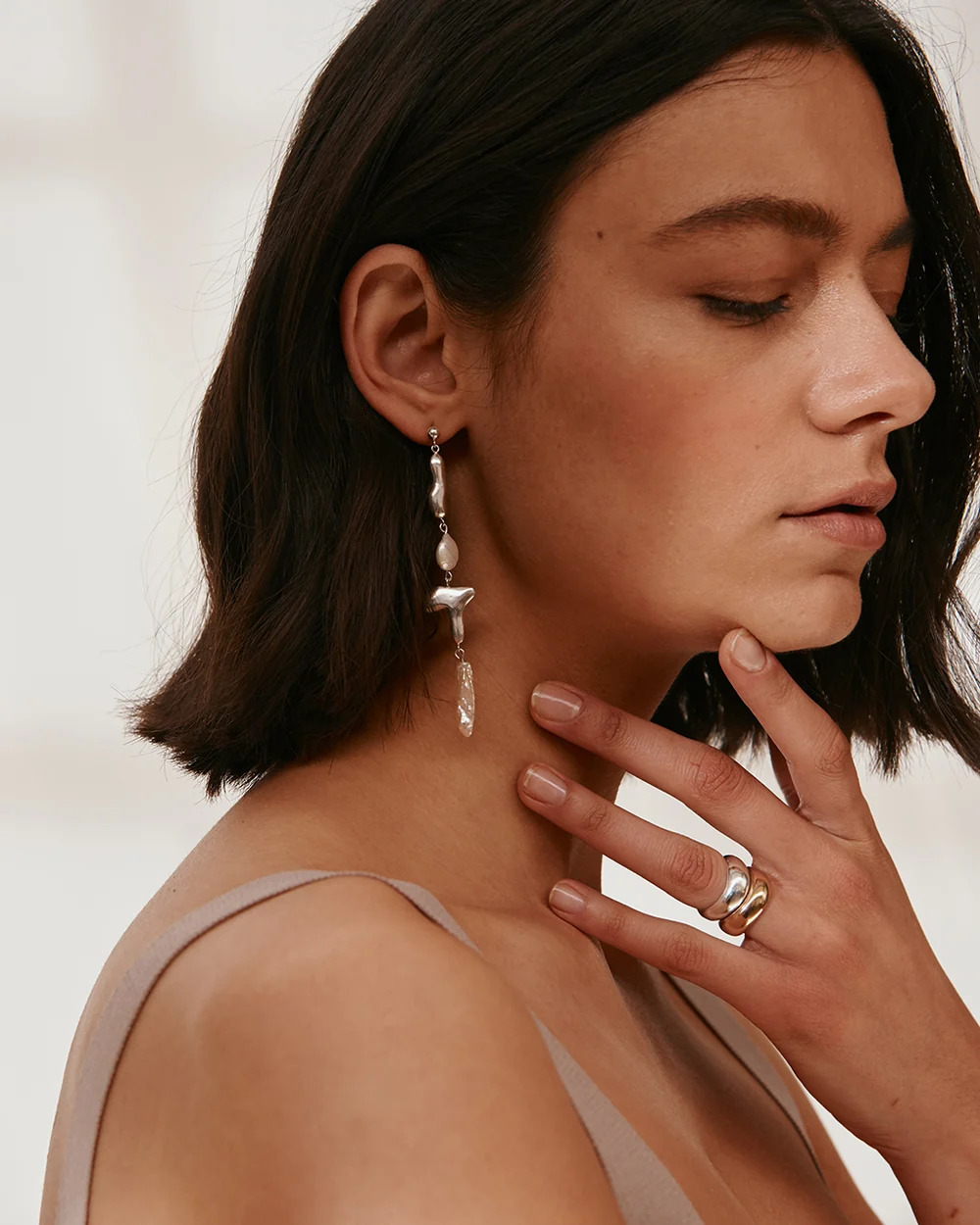 A photo of a model wearing two Onda rings from Carolina de Barros and a long dangling earring