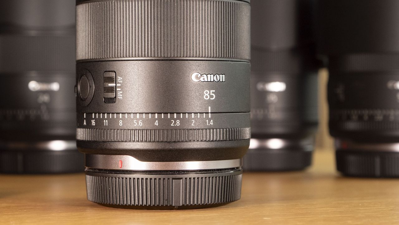 Canon RF 85mm F1.4L VCM lens on a wooden surface, alongside four other Canon F1.4 VCM lenses