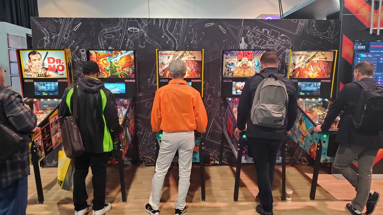 people playing pinball machine lit up