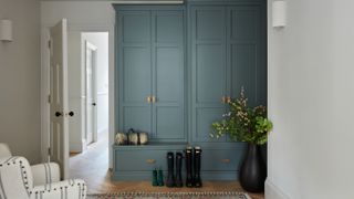 boot room with green blue fitted cupboards and wooden floor