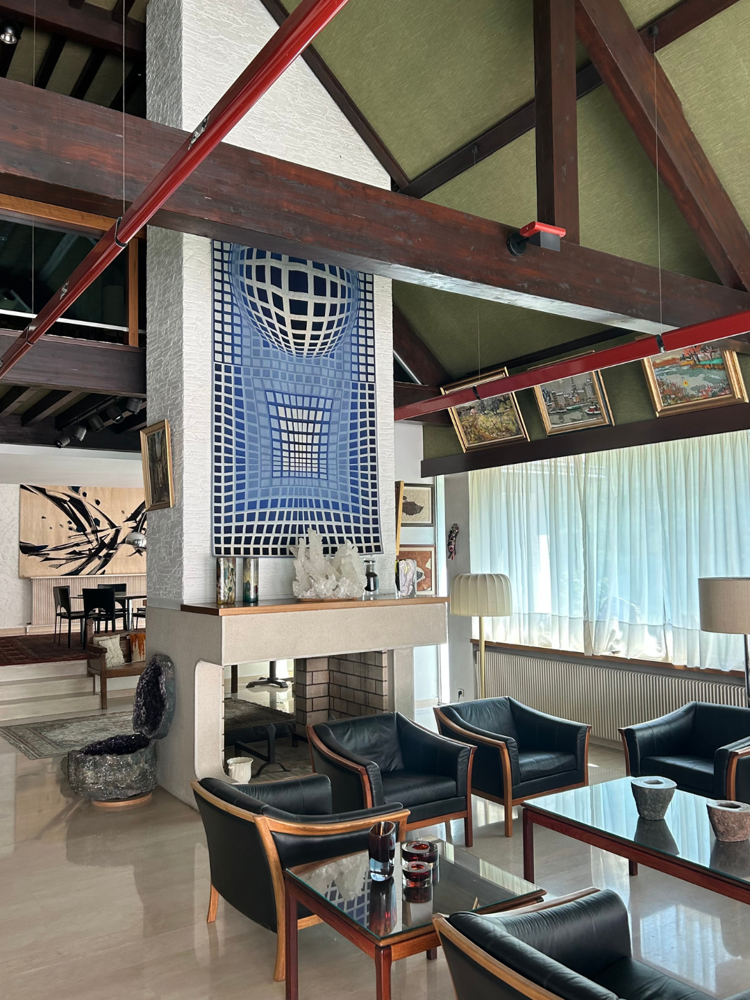 Roset family living room with black leather seating, bold art, exposed beams and collectable design pieces.