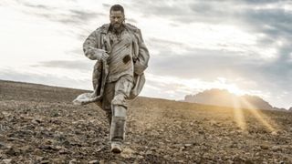 Travis Fimmel as Marcus walking in a desert during the TV series Raised by Wolves.