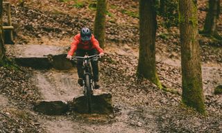 Female mountain biker rides off rock drop