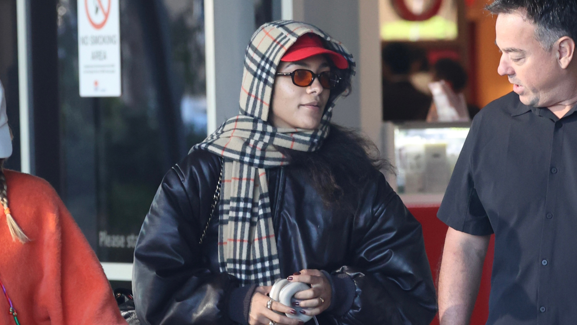 Olivia Dean pictured at the airport wearing a scarf and bomber jacket. 